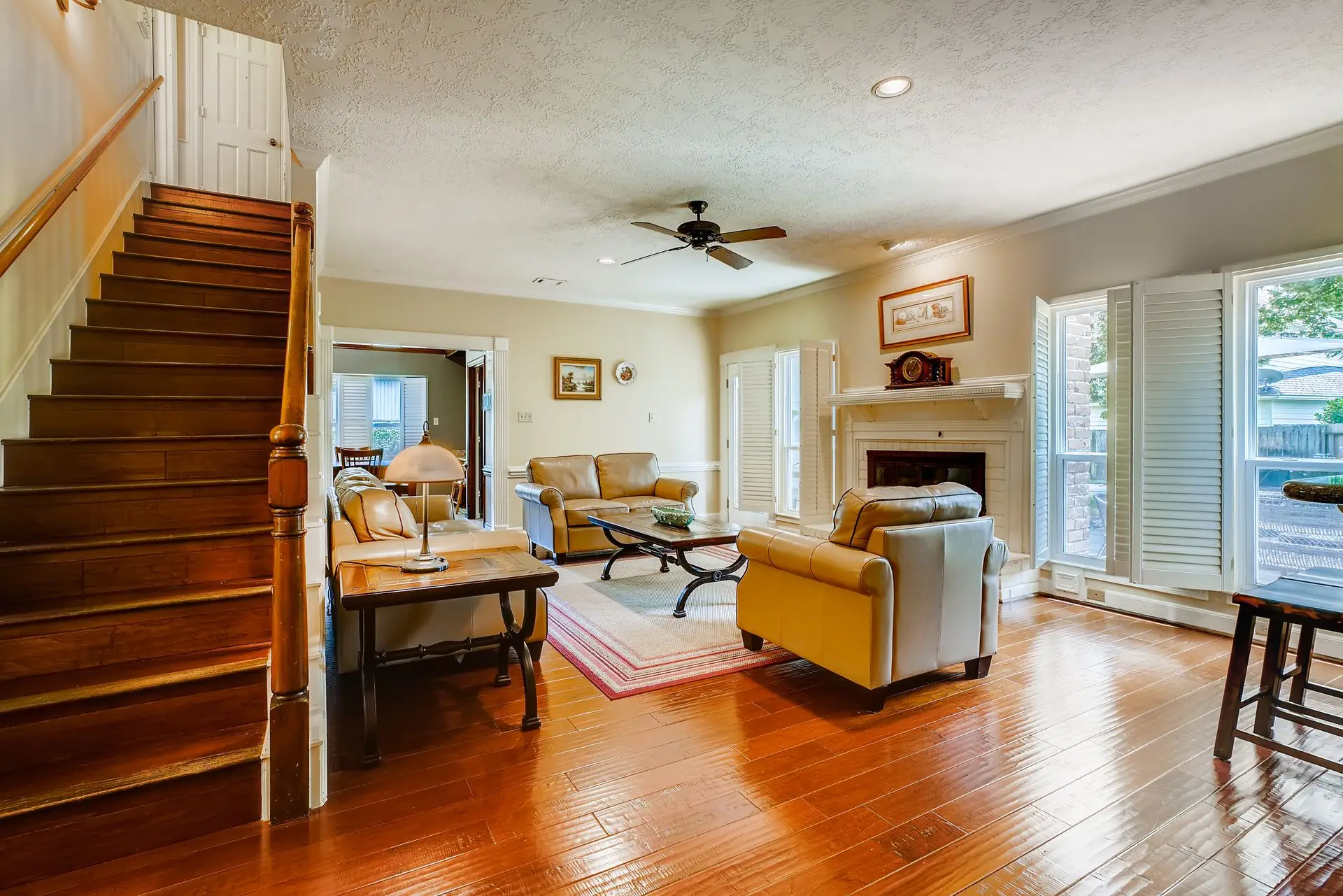Sunlit living room with a hardwood floor and a wooden staircase