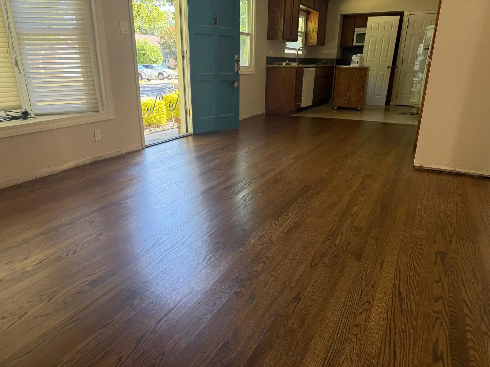 Newly refinished oak hardwood flooring flowing through an open living area and kitchen