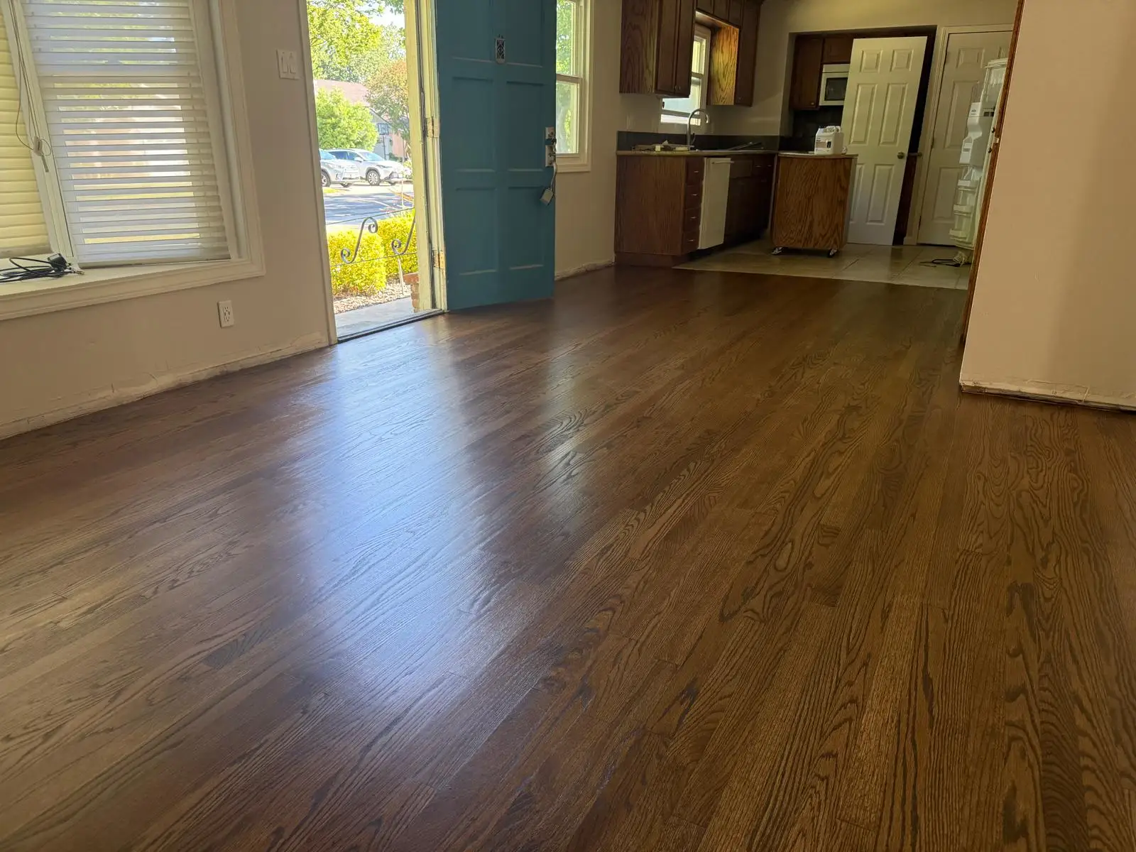Newly refinished oak hardwood flooring flowing through an open living area and kitchen
