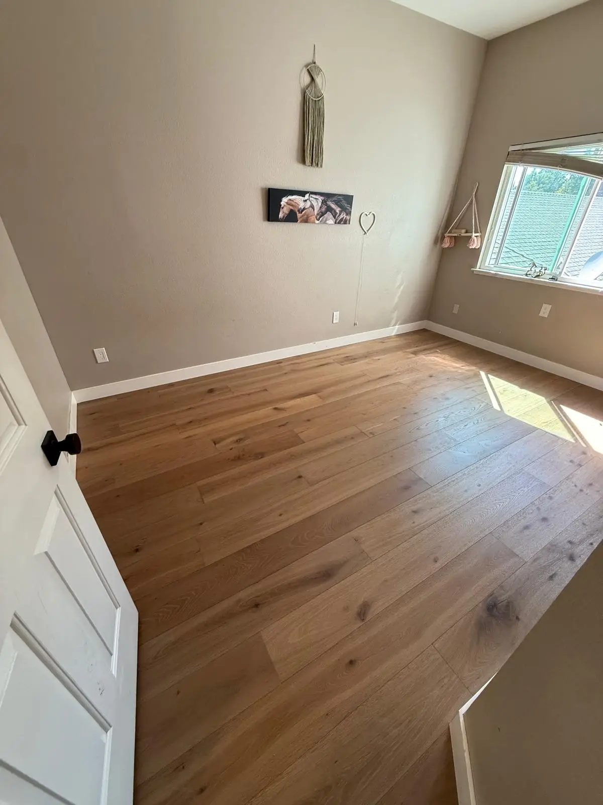 Wide plank engineered oak hardwood flooring installed in a bright bedroom