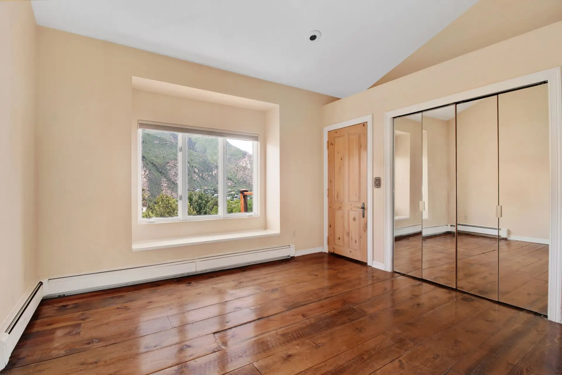 Wide plank hardwood floor in a bright bedroom with a mountain view