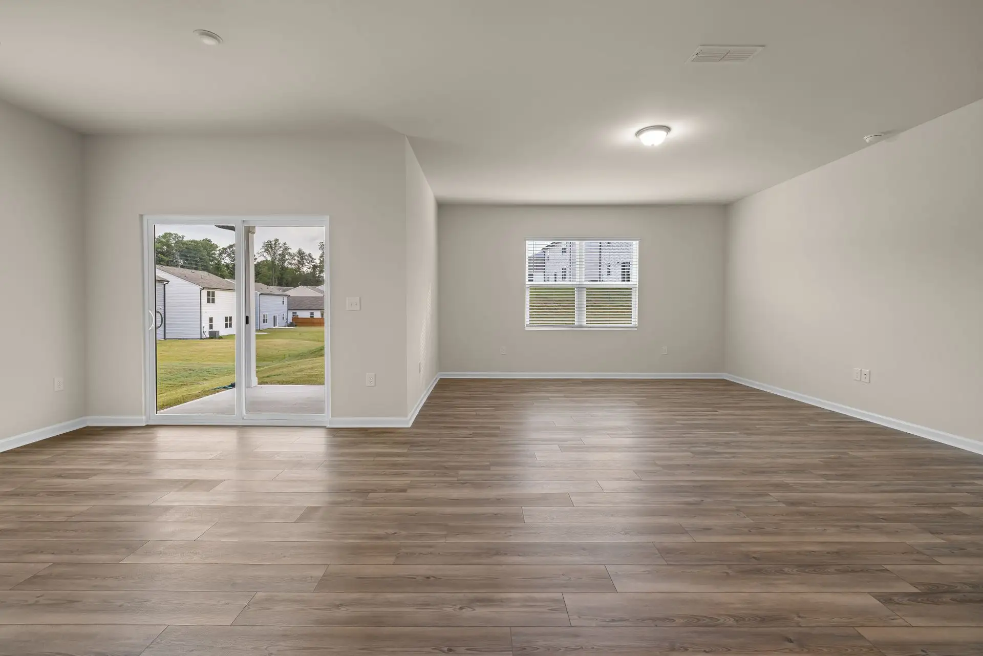 Empty living room with new plank flooring and a sliding glass door