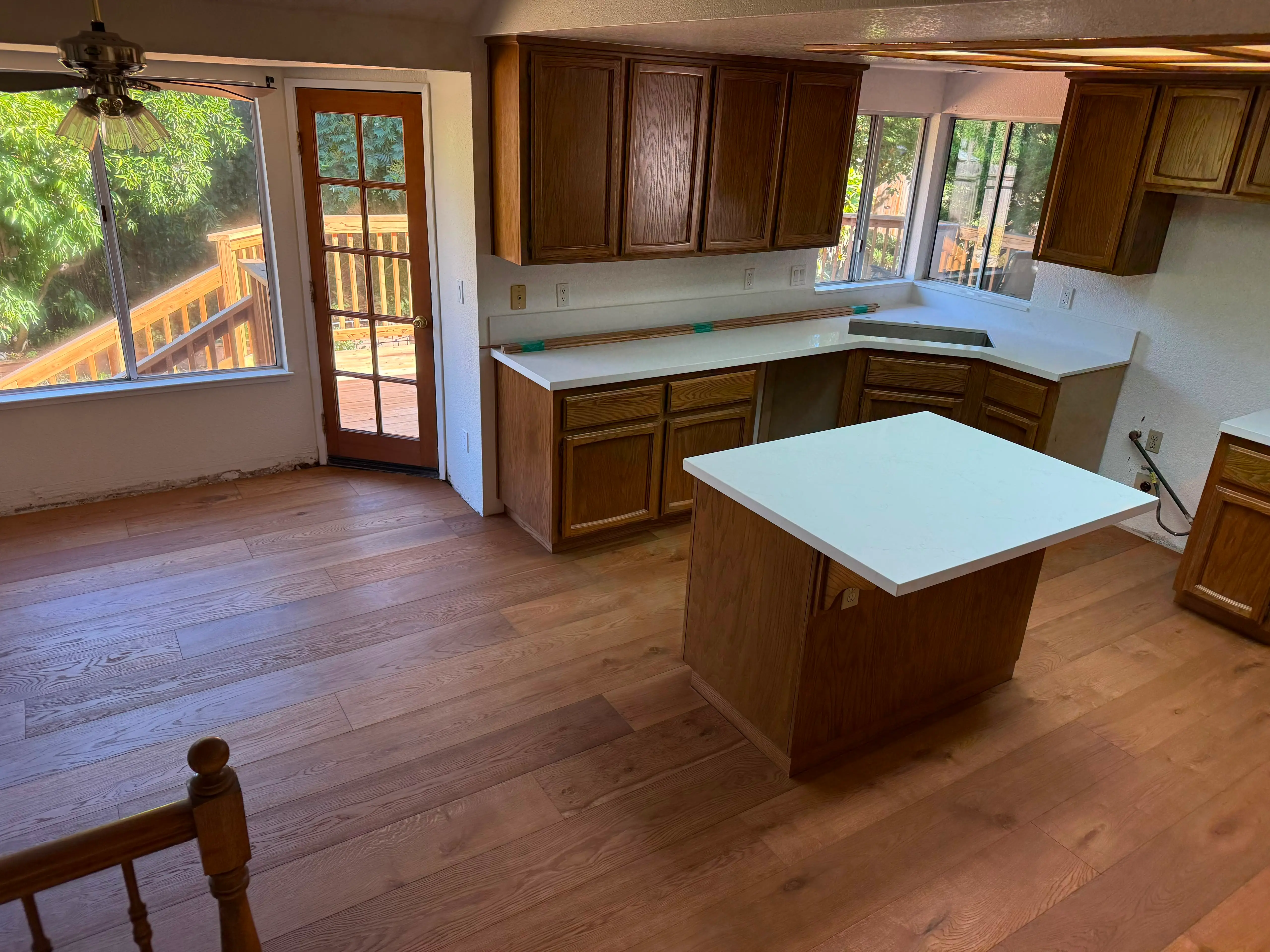 Luxury vinyl plank installation in a sunlit kitchen with white quartz counters