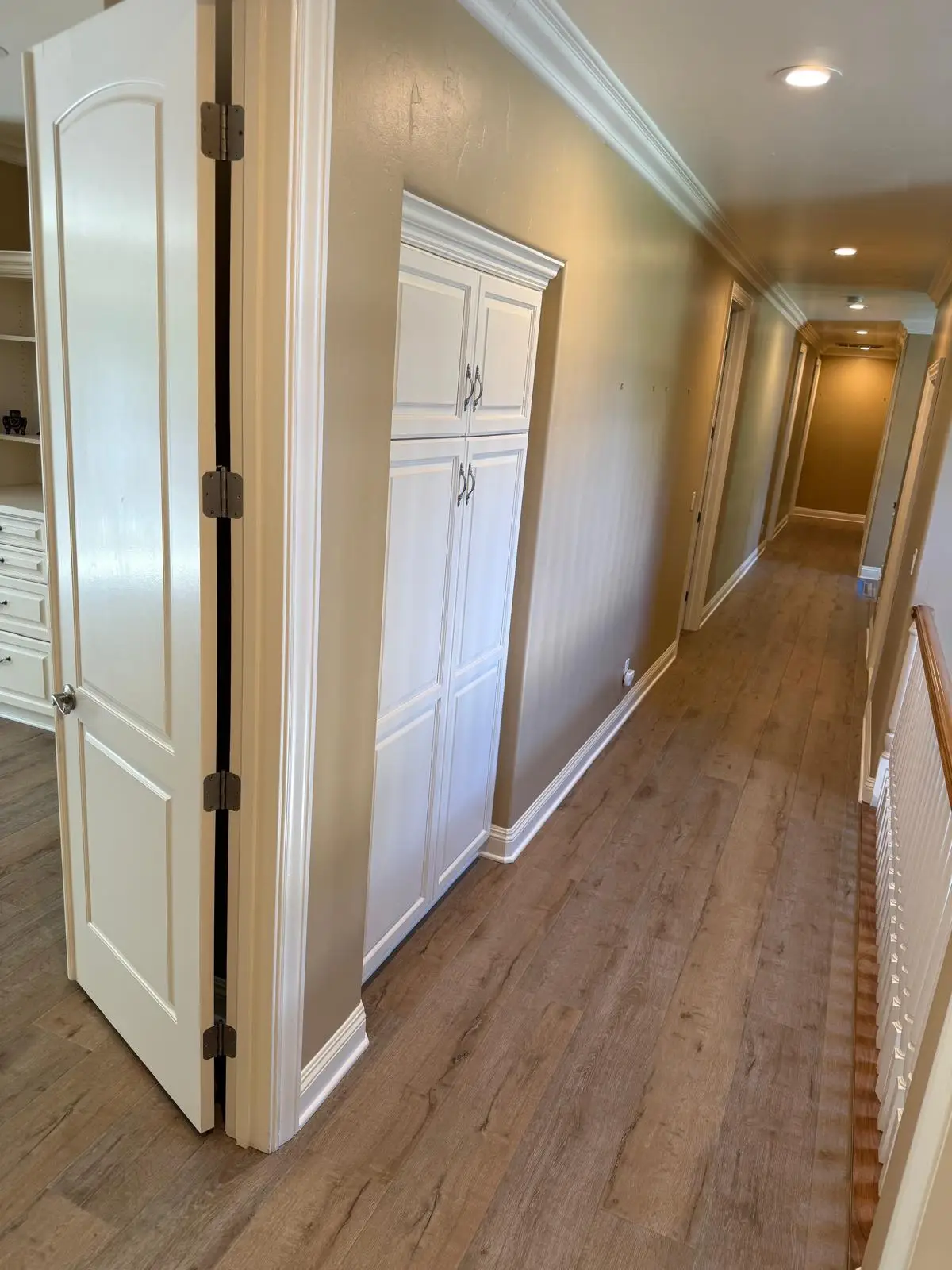 Wide plank LVP vinyl flooring installation in an upstairs hallway with white trim