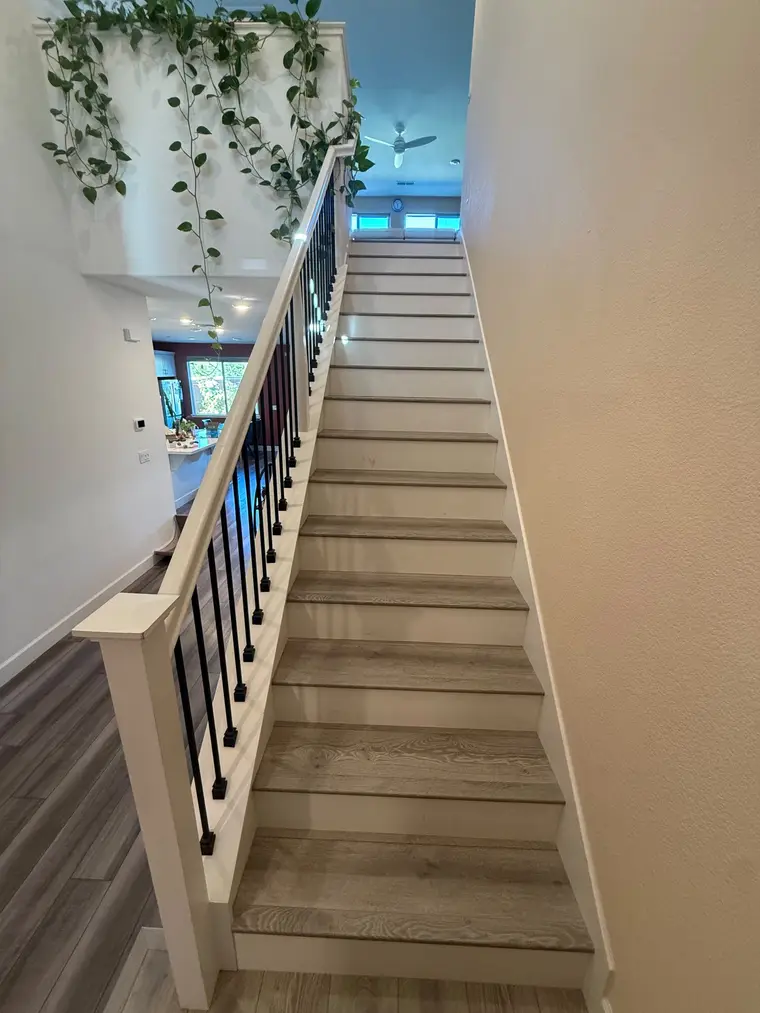 After: Bare particleboard stairs finished with wood-look plank treads and crisp white risers