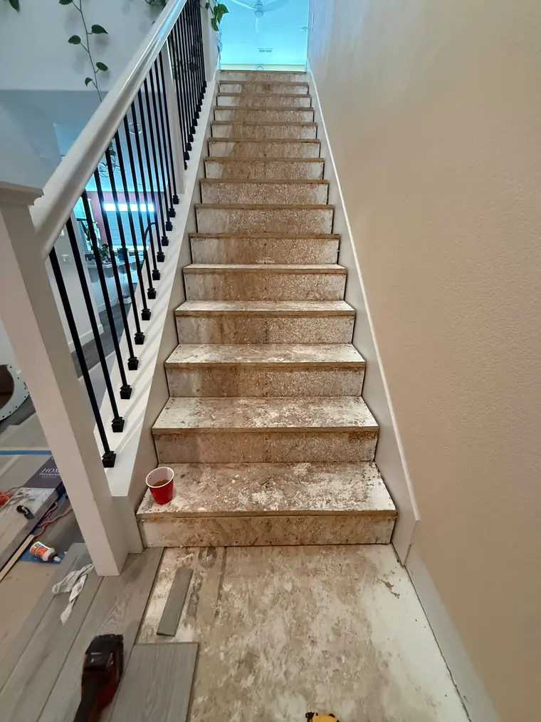 Before: Bare particleboard stairs finished with wood-look plank treads and crisp white risers