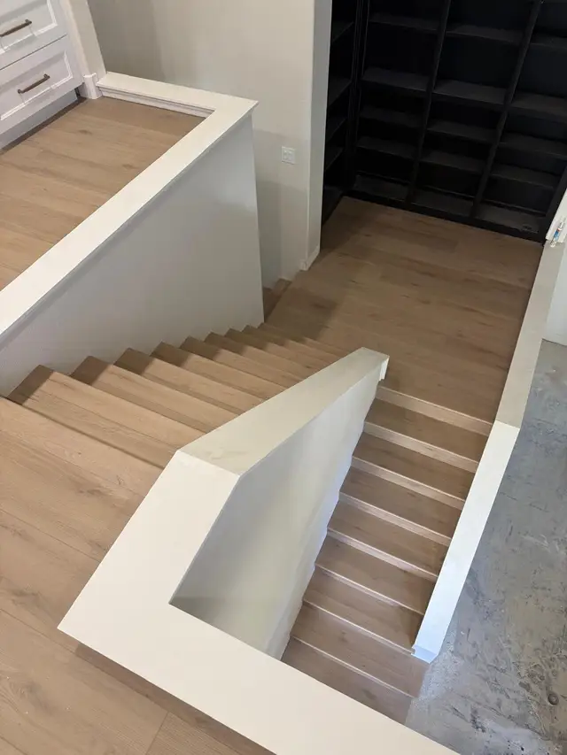 Light oak LVP stair installation with modern black metal railing in Roseville