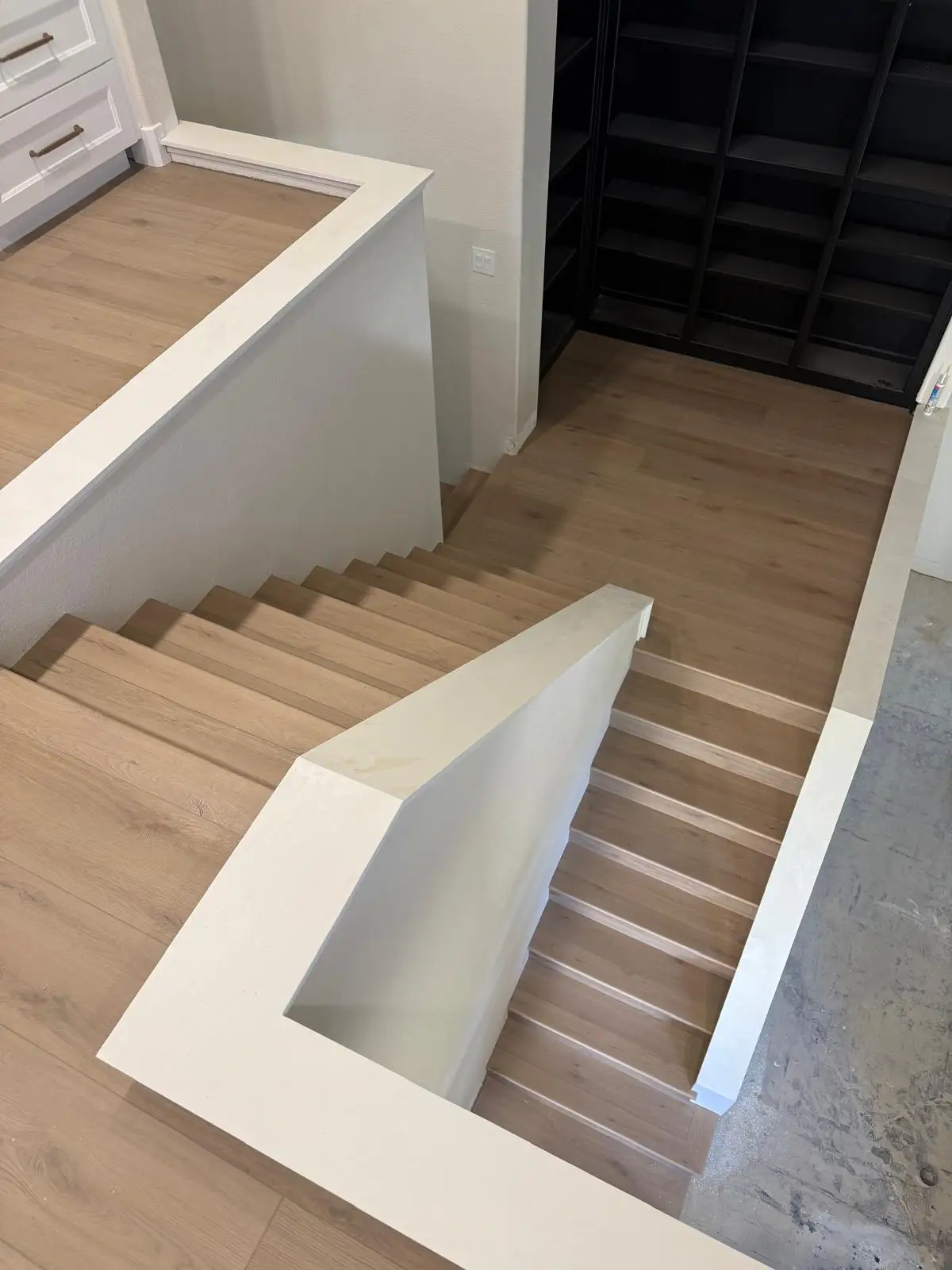 Light oak LVP stair installation with modern black metal railing in Roseville