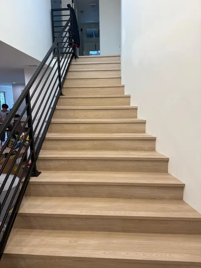 Completed luxury vinyl plank staircase in light oak with black railing
