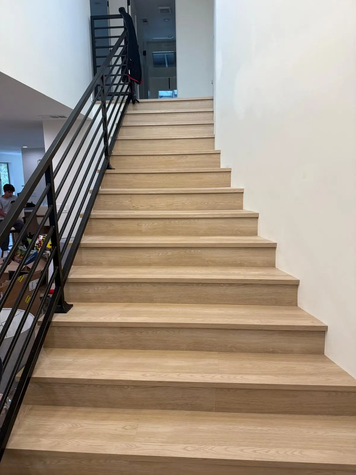 Completed luxury vinyl plank staircase in light oak with black railing
