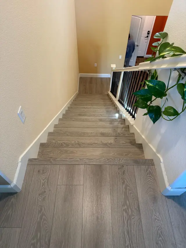 Finished staircase with wide plank LVP flooring treads and iron balusters