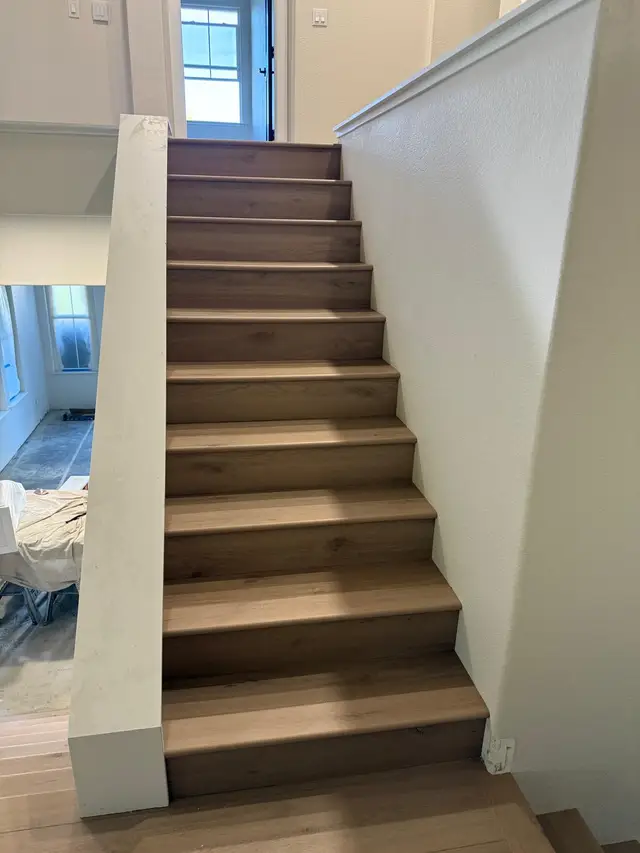 Vinyl plank flooring installed on stairs and upper landing during a home remodel