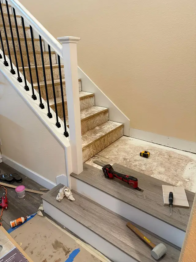 Stair tread installation in progress with new wood-look flooring on lower steps