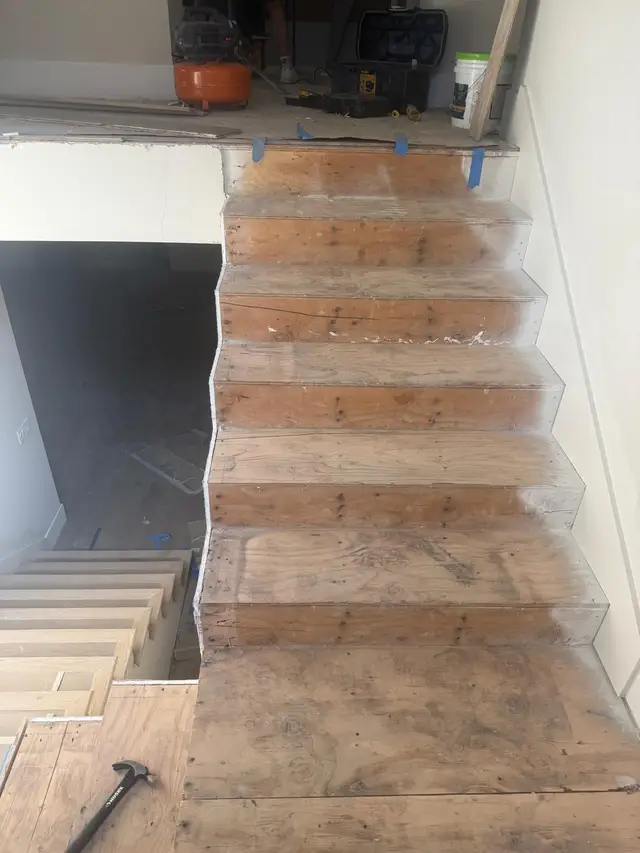 Staircase prepped to bare plywood before hardwood stair tread installation