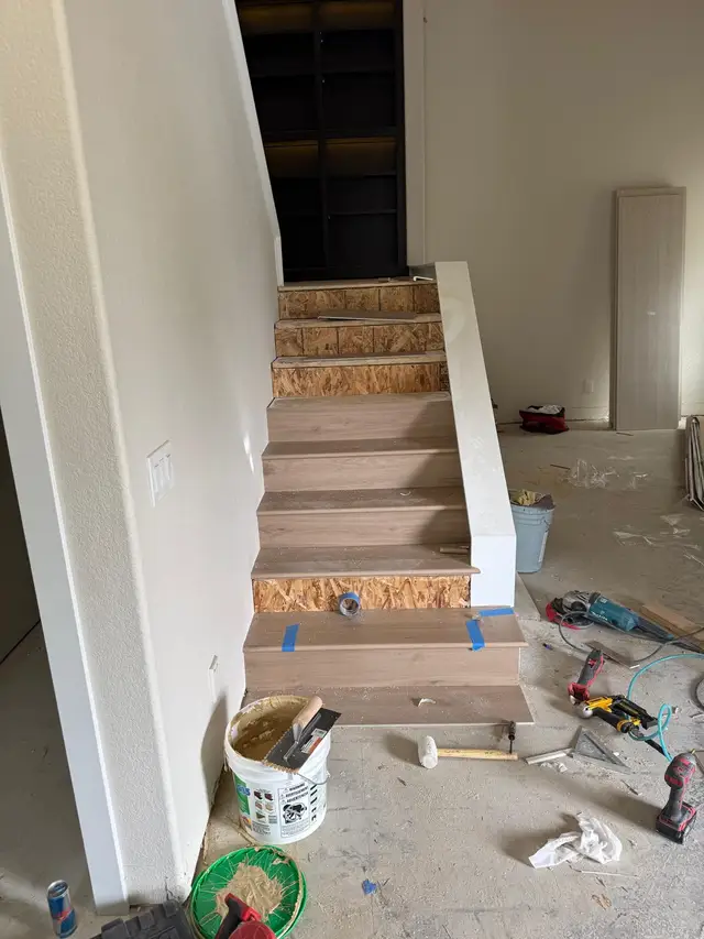 Hardwood stair installation underway with oak treads placed over OSB risers