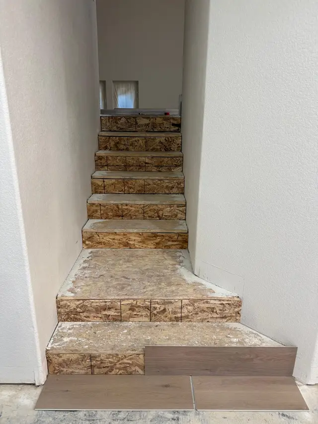 Staircase prepped for luxury vinyl plank installation, bare subfloor treads before flooring